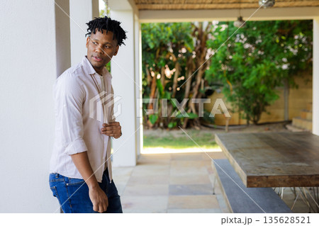 Young man standing on patio, looking away thoughtfully, enjoying outdoor space 135628521