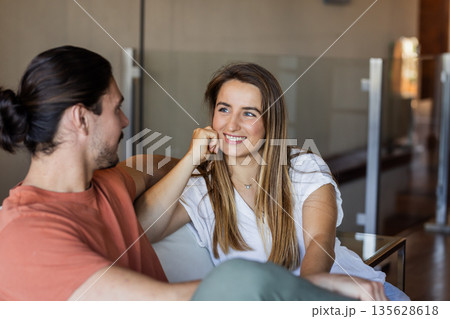 Smiling friends relaxing on sofa, enjoying conversation in cozy living room Smiling friends relaxing on sofa, enjoying conversation in cozy living room 135628618