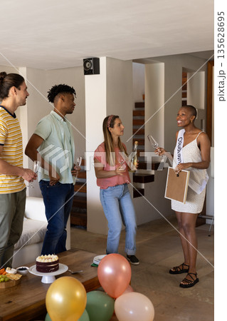 Friends celebrating indoors with champagne and cake, enjoying festive gathering 135628695
