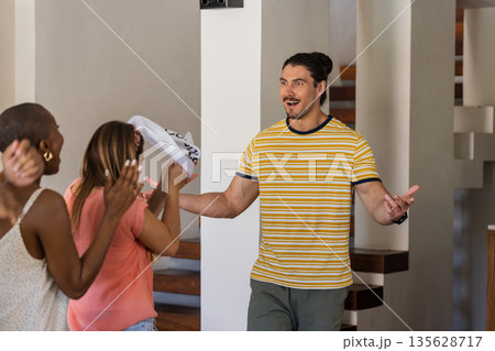 Friends welcoming guest with excitement and joy at home gathering Friends welcoming guest with excitement and joy at home gathering 135628717