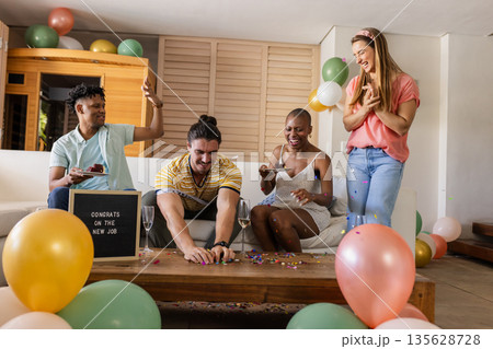 Celebrating new job, diverse friends enjoying party with cake and confetti at home 135628728