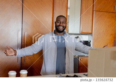 Smiling man welcoming with open arms in modern kitchen with coffee cups Smiling man welcoming with open arms in modern kitchen with coffee cups 135628732