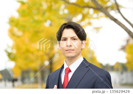 街路樹のあるオフィス街とスーツの男性 135629429