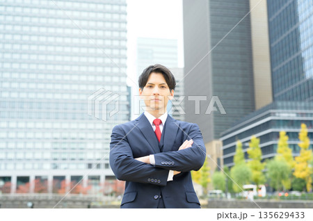 街路樹のあるオフィス街とスーツの男性 135629433