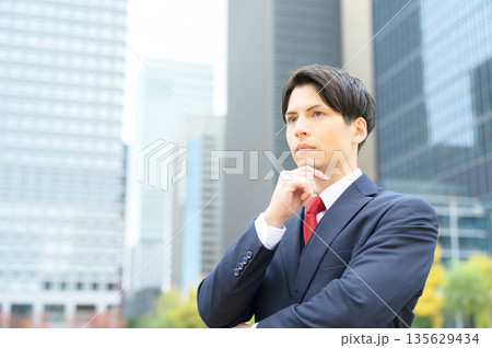 街路樹のあるオフィス街とスーツの男性 135629434
