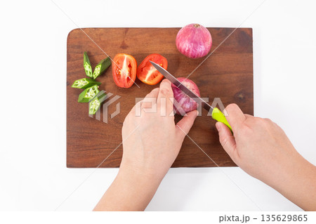 Woman hands cutting fresh red onion and tomatoes, top view Woman hands cutting fresh red onion and tomatoes, top view 135629865