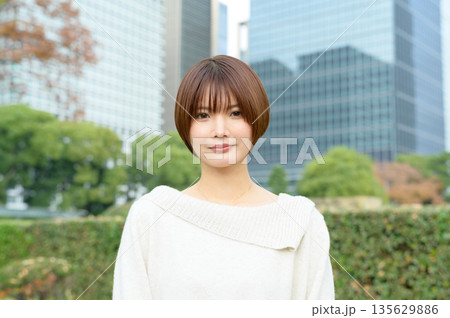 オフィス街を背景に微笑むショートカットの日本人女性 135629886