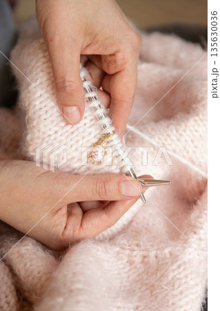 Woman enjoying knitting as relaxing hobby with yarn and needles in warm cozy home environment Woman enjoying knitting as relaxing hobby with yarn and needles in warm cozy home environment 135630036