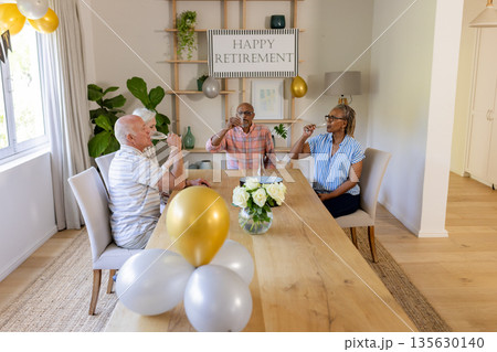Senior friends celebrating retirement with champagne in bright, cheerful dining room Senior friends celebrating retirement with champagne in bright, cheerful dining room 135630140