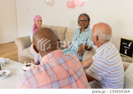 Senior friends celebrating cancer survivor with cake and conversation in living room 135630164