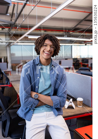 Smiling African American man in casual attire standing in modern office workspace Smiling African American man in casual attire standing in modern office workspace 135630224