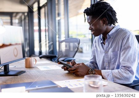 African American man using tablet and computer at office, analyzing data charts African American man using tablet and computer at office, analyzing data charts 135630242