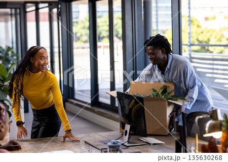 Unpacking box in modern office, African American colleagues smiling and collaborating Unpacking box in modern office, African American colleagues smiling and collaborating 135630268