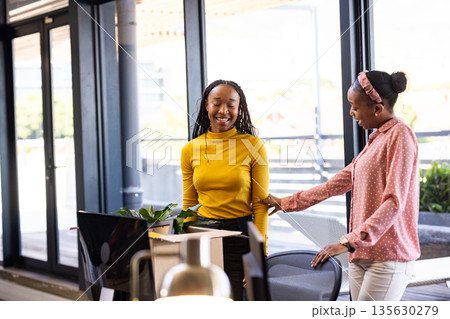African American women in office smiling and discussing creative business ideas African American women in office smiling and discussing creative business ideas 135630279