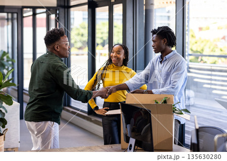 Celebrating successful collaboration, colleagues shaking hands in modern office setting 135630280