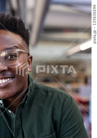 Smiling man in glasses wearing green shirt at modern office workspace Smiling man in glasses wearing green shirt at modern office workspace 135630299