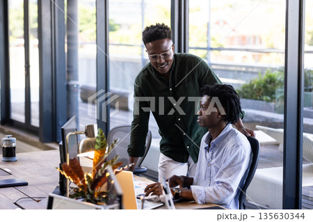 Collaborating in modern office, two men discussing project on laptop screen Collaborating in modern office, two men discussing project on laptop screen 135630344