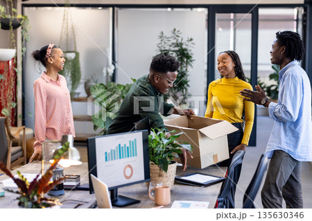 Team celebrating new project in modern office, unpacking box with excitement Team celebrating new project in modern office, unpacking box with excitement 135630346