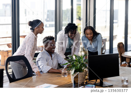 Collaborating on project, African American team discussing ideas and smiling at office Collaborating on project, African American team discussing ideas and smiling at office 135630377