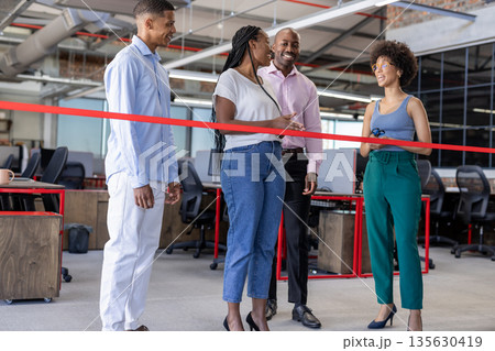 Celebrating office opening, diverse business team cutting ribbon, smiling together 135630419