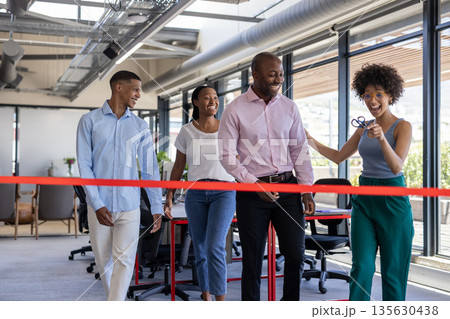Celebrating office opening, business team cutting ribbon together, smiling happily 135630438