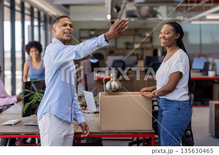 Colleagues unpacking box and laughing together in modern office workspace Colleagues unpacking box and laughing together in modern office workspace 135630465