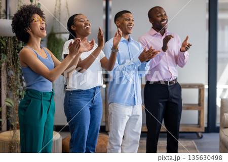 Diverse group of professionals clapping and smiling in modern office setting Diverse group of professionals clapping and smiling in modern office setting 135630498