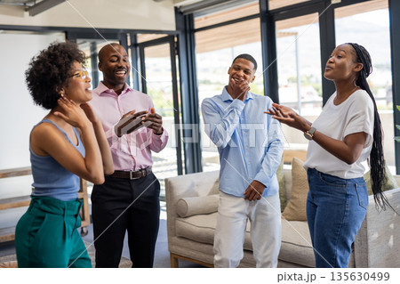 Colleagues laughing and chatting in modern office during casual team meeting 135630499