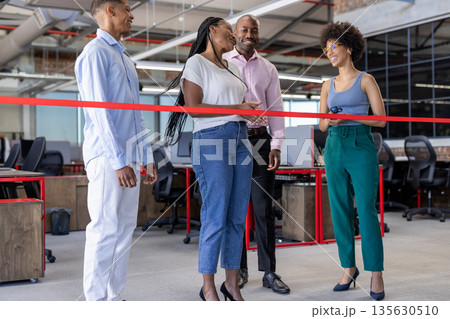 African American colleagues cutting ribbon in modern office, celebrating new opening 135630510