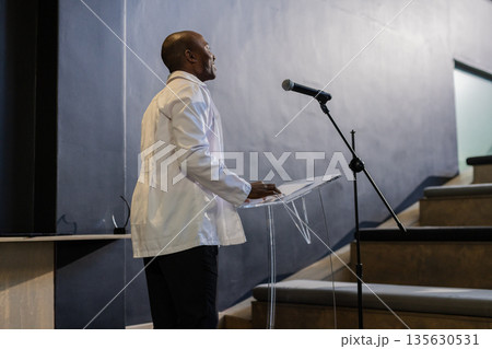 Presenting confidently, businessman speaking at podium during professional conference Presenting confidently, businessman speaking at podium during professional conference 135630531