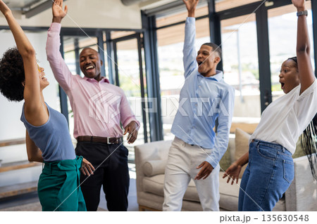 Colleagues celebrating success together in modern office, raising hands joyfully Colleagues celebrating success together in modern office, raising hands joyfully 135630548