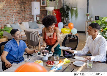 Serving cake to colleagues, African American woman smiling during office celebration 135630572