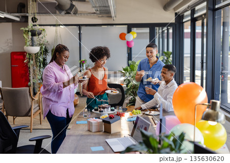 In office, diverse colleagues sharing cake and conversation during work break 135630620