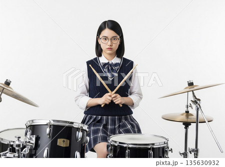 ドラムセットの前でスティックをクロスさせてポーズをとる眼鏡の女子高生ドラマー 135630932
