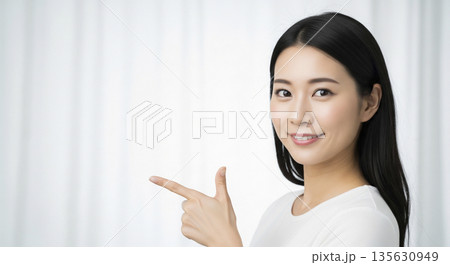 白い服を着て横を向き指差し確認をする笑顔の日本人女性 135630949