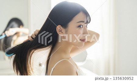 逆光の中で輝く美しい黒髪をブラシで梳かす日本人女性の横顔 135630952