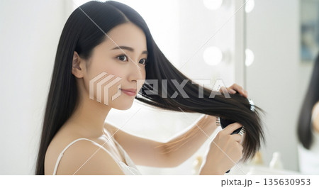 長い黒髪の毛先をブラシで丁寧に整える日本人女性のポートレート 135630953