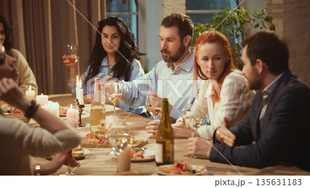 Friends in their thirties talking during intimate dinner with wine. Friends in their thirties talking during intimate dinner with wine. 135631183