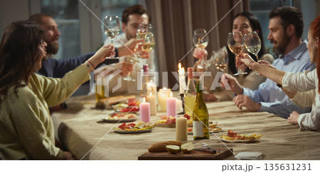 Friends talking over wine sitting around table in cozy home interior. 135631231