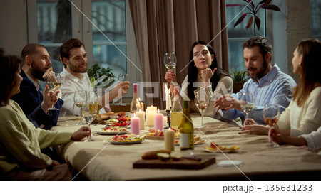Friends enjoying wine tasting during evening gathering 135631233
