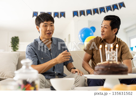 Celebrating birthday, two men having conversation with cake and decorations at home Celebrating birthday, two men having conversation with cake and decorations at home 135631502