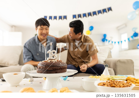 Celebrating 18th birthday, father and son sharing joyful moment at home party Celebrating 18th birthday, father and son sharing joyful moment at home party 135631505