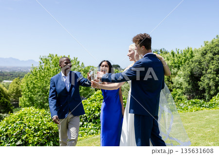 Celebrating wedding outdoors, friends toasting with champagne and smiling together 135631608