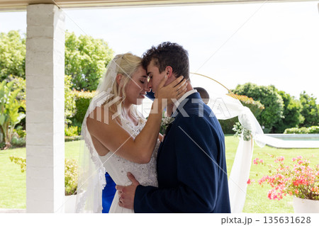 Embracing lovingly, bride and groom in outdoor wedding ceremony surrounded by nature Embracing lovingly, bride and groom in outdoor wedding ceremony surrounded by nature 135631628