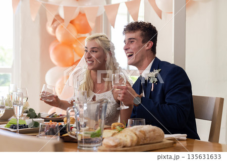 Bride and groom joyfully toasting at wedding reception with festive decorations Bride and groom joyfully toasting at wedding reception with festive decorations 135631633