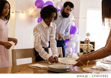 Family setting table for bar mitzvah with festive decorations and cupcakes 135631682