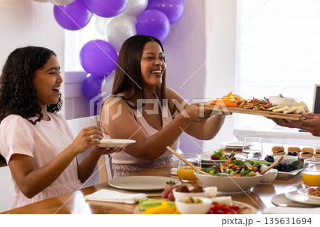 Family sharing appetizers and smiling together at festive meal around dining table Family sharing appetizers and smiling together at festive meal around dining table 135631694