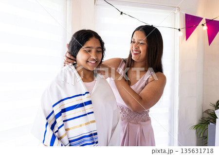 Helping daughter with prayer shawl, mother celebrating religious tradition at home Helping daughter with prayer shawl, mother celebrating religious tradition at home 135631718