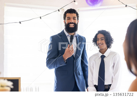 Man in suit speaking into microphone with smiling boy at celebration event Man in suit speaking into microphone with smiling boy at celebration event 135631722