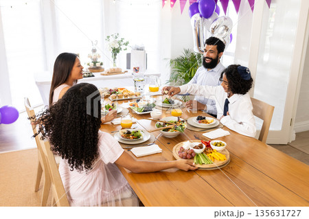 Celebrating special occasion, family sharing festive meal with joy and laughter Celebrating special occasion, family sharing festive meal with joy and laughter 135631727